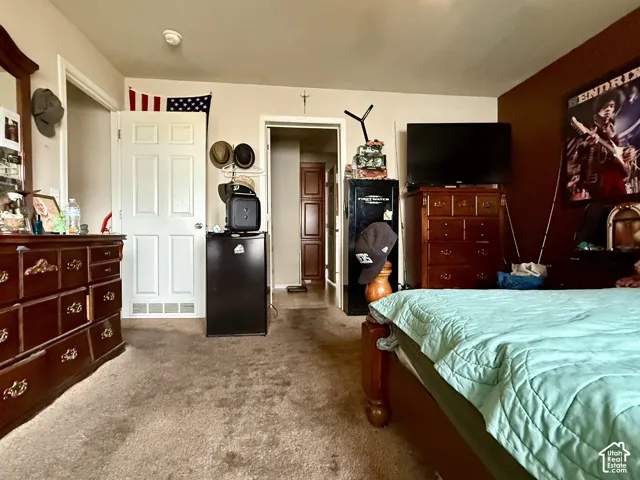 Room featuring carpeted flooring, a six-panel door, and a built-in storage cabinet with recessed panels