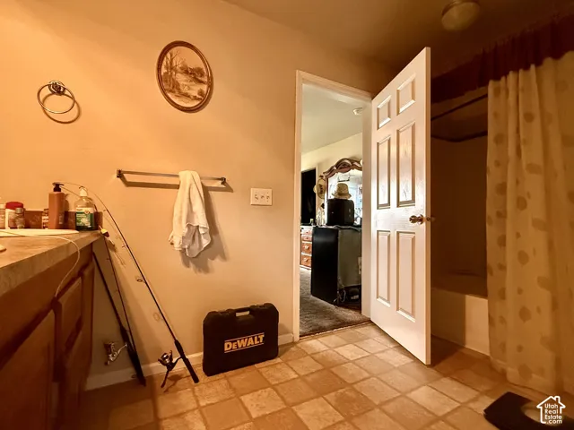 Bathroom featuring a vanity with countertop, six-panel interior door, tiled flooring, and a shower-tub combination
