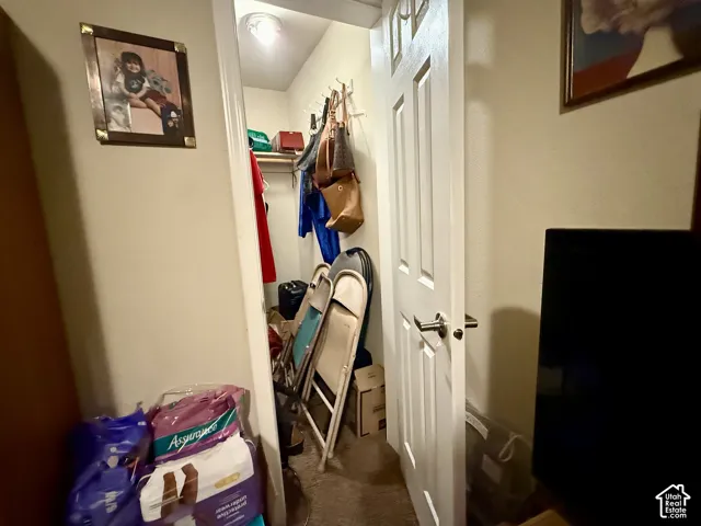 Reach-in closet featuring a wood shelf, a wall-mounted hook rack, and a six-panel interior door