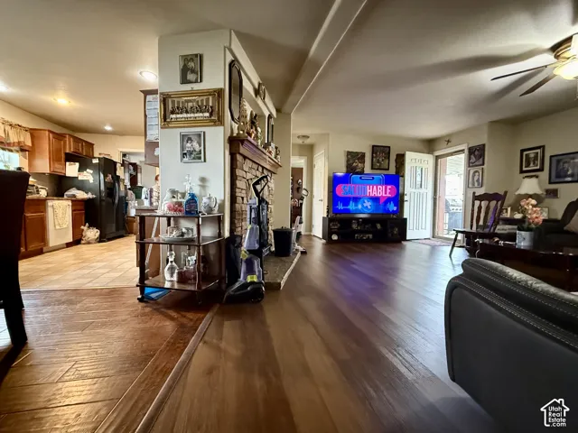Open-concept living space featuring wood-finish flooring, a central brick fireplace, wooden cabinetry, and recessed lighting