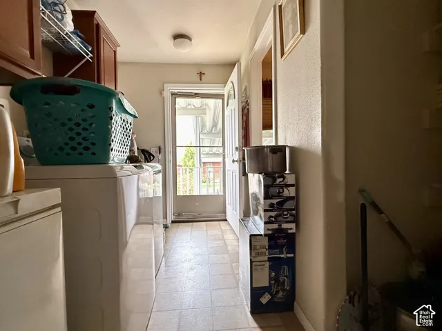 Utility room featuring vinyl tile flooring, upper wood cabinetry, and a storm door providing exterior access