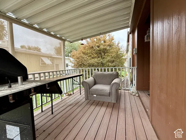 Covered deck featuring wood-finish flooring, white railing, and a corrugated metal patio cover