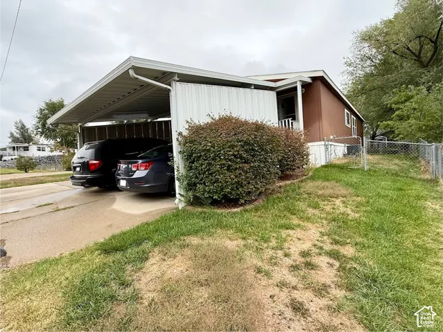 Exterior featuring a covered metal carport, solid-surface siding, and chain-link fencing