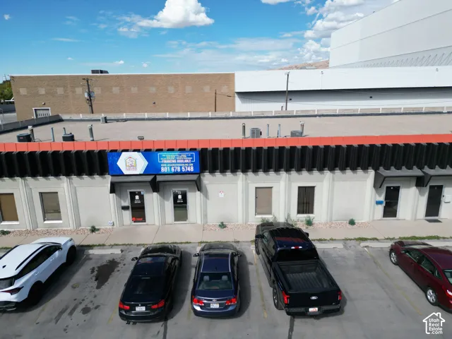 Single-story commercial exterior featuring a flat roof, concrete facade, multiple glass-panel entry doors, and dedicated asphalt parking