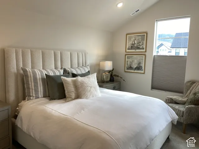 Vaulted ceiling, recessed lighting, large window with cellular shades, and neutral wall tones