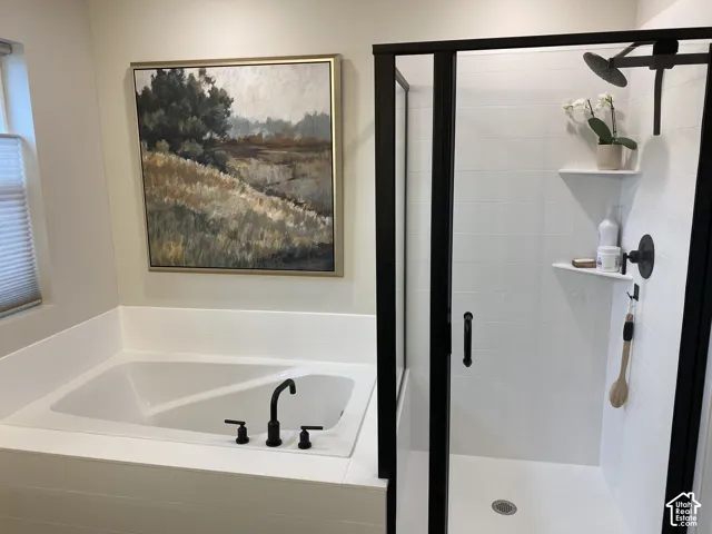 Built-in soaking tub with matte black fixtures, alongside a glass-enclosed shower featuring matte black framing and fixtures