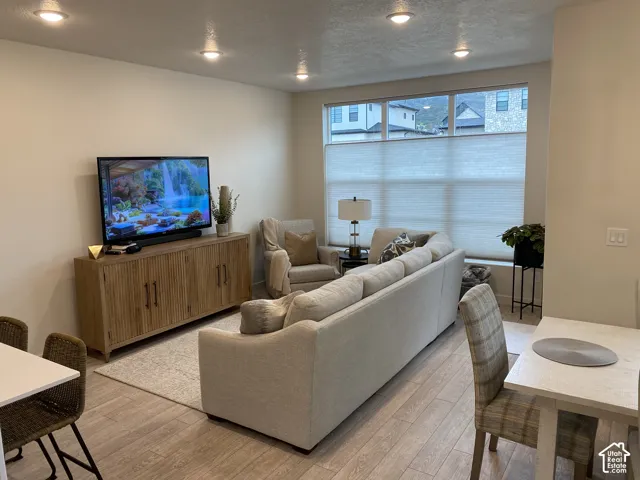 Recessed ceiling lighting, wood-finish flooring, and large windows with cellular shades