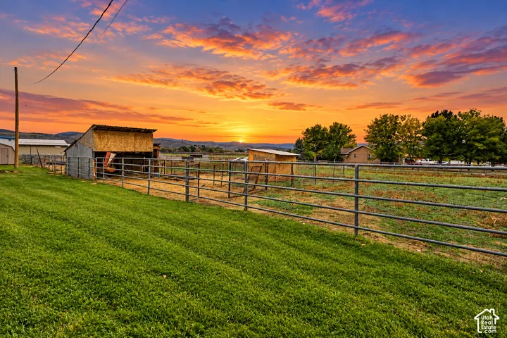 Expansive grounds featuring metal pipe fencing, multiple open-air structures, manicured lawn, and mountain horizons