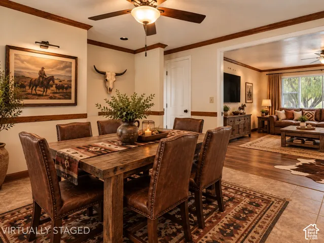 Dining area featuring neutral wall paint, wood-finish chair rail molding, ceiling-mounted light fixture with fan, and tile flooring