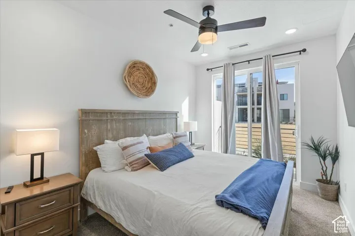 Bedroom featuring a matte black ceiling fan, neutral carpeting, and a glass sliding door with curtain rod hardware