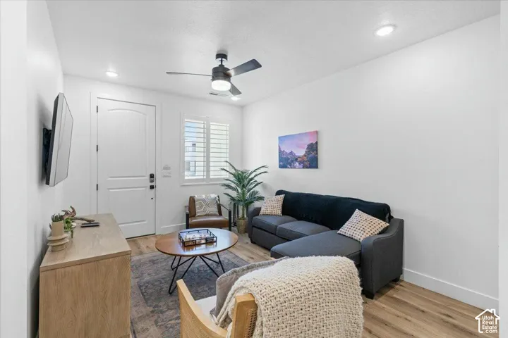 Room featuring wood-finish flooring, recessed lighting, a ceiling fan with integrated light, and a window with plantation-style shutters