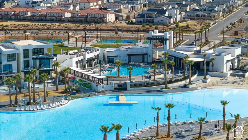 Expansive community recreation area featuring a large swimming lagoon, secondary pool, multiple covered ramadas, palm tree landscaping, and paved hardscaping