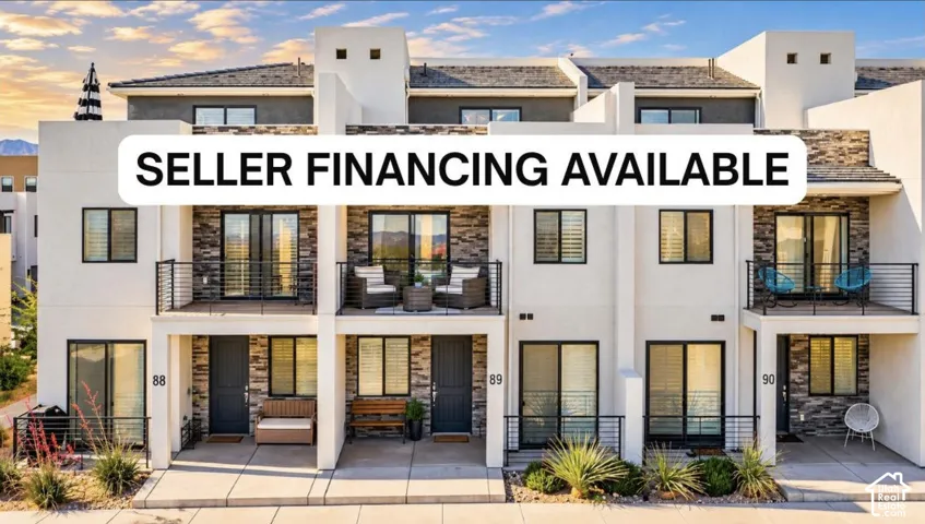 Multi-level residential exterior featuring smooth stucco finish, stone veneer accents, upper-level balconies with horizontal cable railings, and concrete ground-level patios