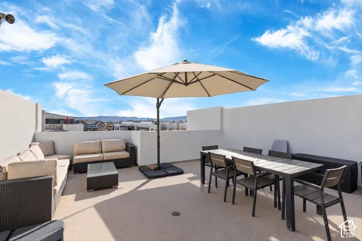 Expansive rooftop deck featuring a textured composite surface, solid stucco perimeter walls, and mountain scenery