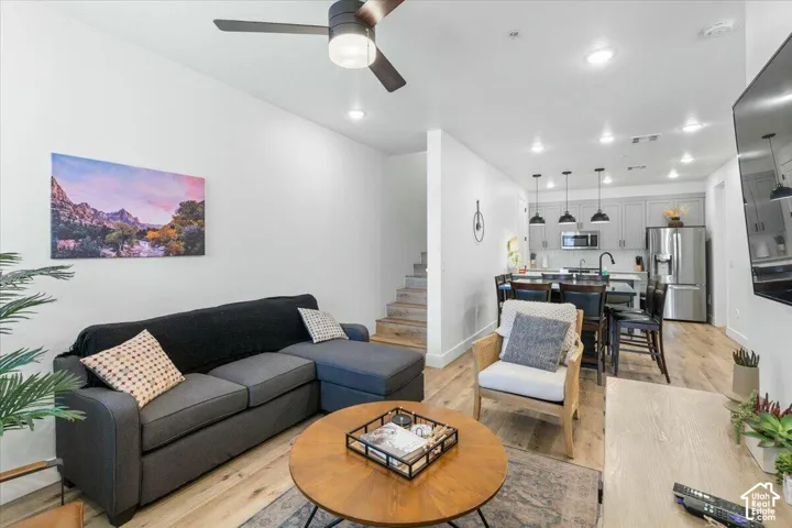 Open-concept layout featuring wood-finish flooring, recessed lighting, a modern ceiling fan, grey shaker-style cabinetry, and stainless-steel appliances