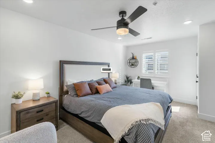Neutral-toned carpeted flooring, matte black ceiling fan with integrated lighting, recessed ceiling lights, and plantation shutter window coverings
