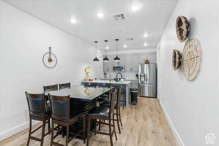 Kitchen featuring gray cabinetry, stainless steel appliances, recessed lighting, pendant light fixtures, and wood-finish flooring