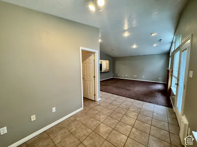 Vaulted ceilings, ceramic tile flooring, recessed lighting, and glass-paneled exterior door