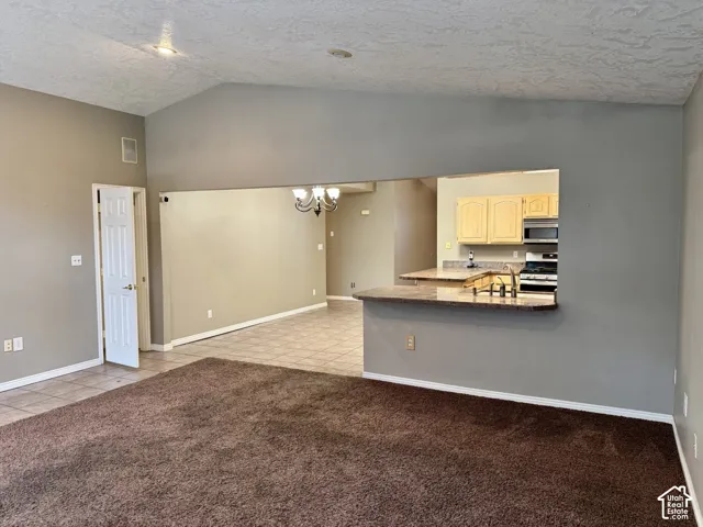 Vaulted ceilings, a pass-through kitchen window, breakfast bar with stone-finish countertop, and neutral carpeting