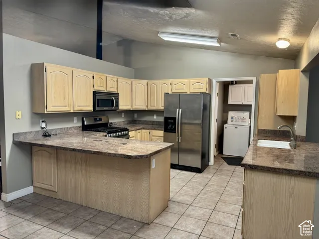 Kitchen featuring light wood-finish cabinetry, stone-finish countertops, stainless steel refrigerator, built-in microwave, and tile flooring