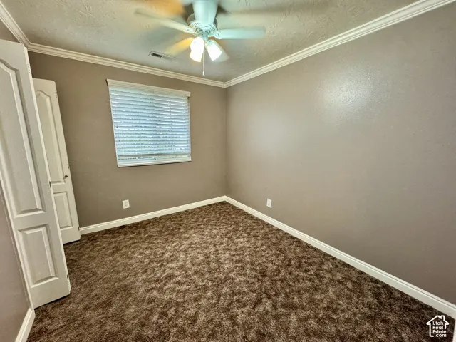 Room featuring carpeting, crown molding, a ceiling fan with integrated lighting, and a multi-panel door