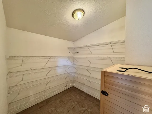 Storage area featuring multi-tier wire shelving, neutral floor tile, and a flush-mount ceiling light fixture