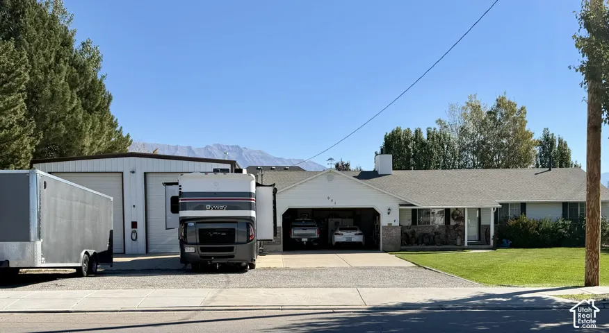 Exterior featuring a neutral-toned facade, expansive gravel parking area, attached two-car garage, and detached oversized garage structure