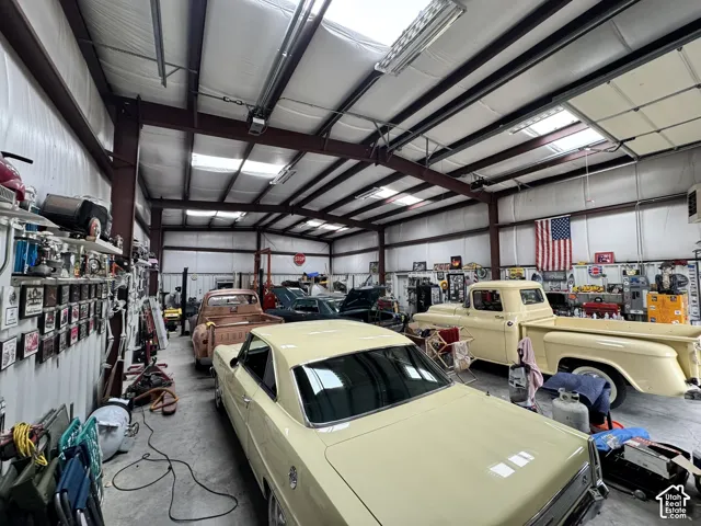 Expansive workshop featuring a steel-frame structure, vaulted ceilings with integrated skylights, polished concrete flooring, and high-clearance overhead doors