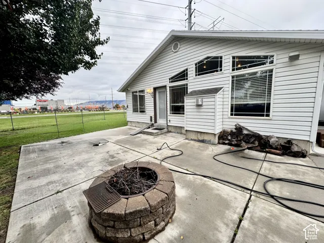Concrete patio featuring a circular stone-block fire pit and white vinyl siding exterior with geometric fixed-pane windows