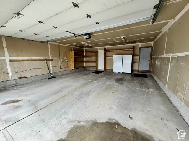 Multi-car garage featuring a concrete floor, built-in wooden shelving, and overhead lighting