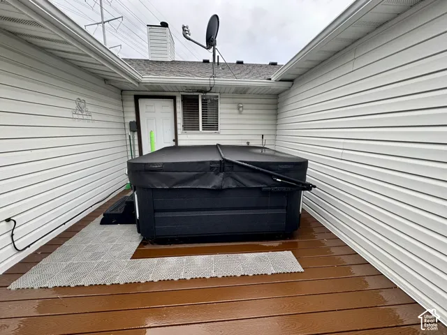 Exterior deck featuring composite wood-finish decking and integrated hot tub with rigid cover