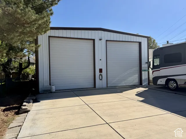 Detached metal-sided garage featuring two overhead doors and an expansive concrete driveway
