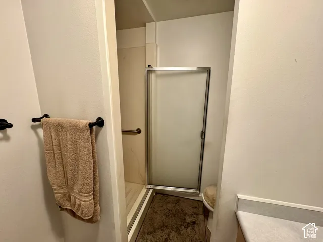 Shower stall featuring a frosted glass door and a wall-mounted grab bar, complemented by a matte black towel ring