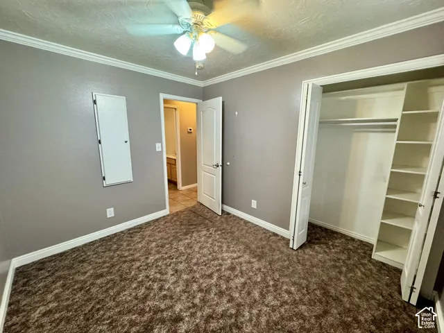 Room featuring crown molding, neutral wall tones, a ceiling fan with integrated lighting, and a closet with built-in shelving