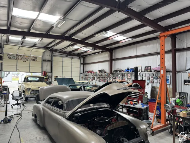Expansive industrial workshop featuring exposed steel beam construction, high-clearance vaulted ceilings, concrete flooring, and multiple overhead sectional doors