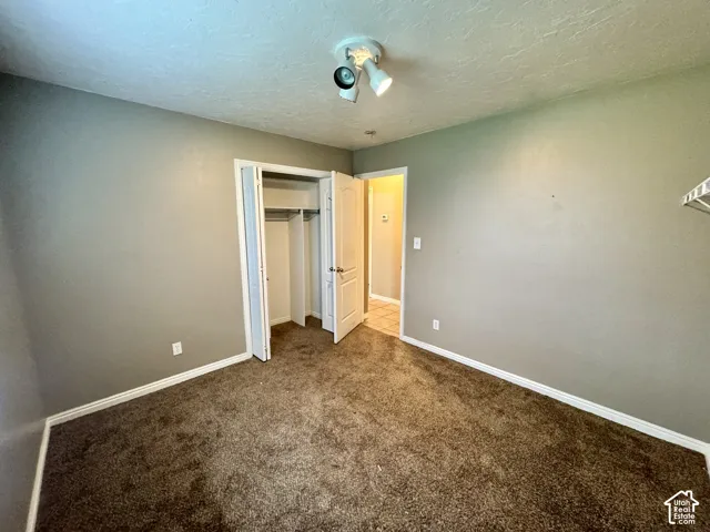 Neutral-toned interior space featuring carpeted flooring, a multi-bulb ceiling light fixture, and a built-in closet with bifold doors