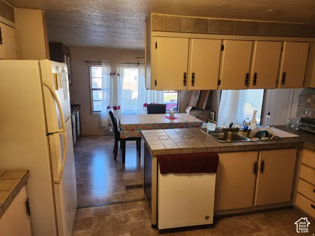 Kitchen featuring tile countertops, stainless steel sink, wood-finish cabinetry, and built-in appliances
