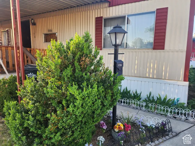 Exterior featuring corrugated metal siding, decorative red shutters, a metal-framed covered entry, and a post-mounted exterior lamp