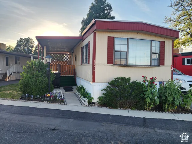 Exterior featuring vertical siding, an attached covered carport, and a front entrance with wood-lattice accents