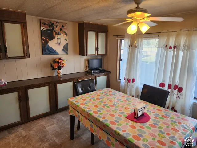 Built-in wood cabinetry with glass-panel inserts, laminate countertop, ceiling-mounted light fixture with fan, and windows with horizontal blinds