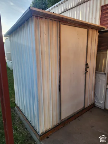 Outdoor storage shed with corrugated metal siding, metal-frame door, and concrete base foundation