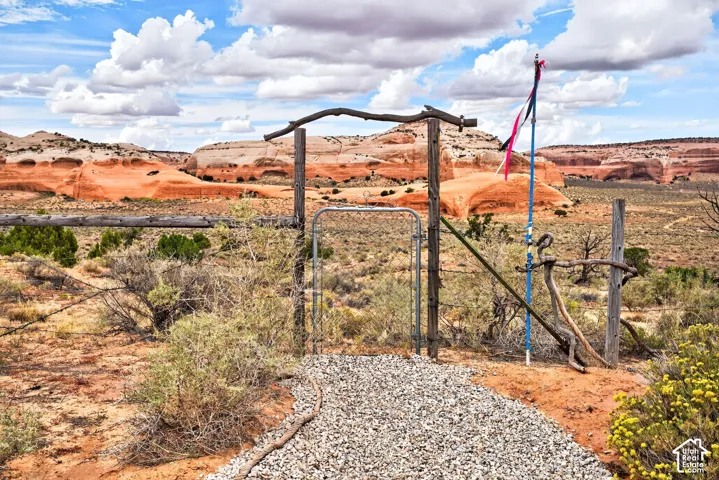 Gravel pathway leading to a rustic wooden gate and chain-link fence