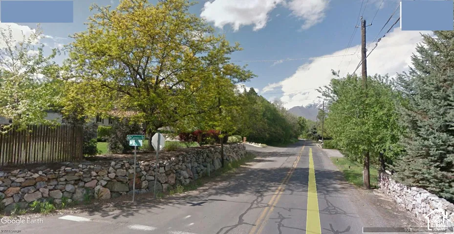 Natural stone retaining wall, mature deciduous and coniferous trees, and mountain backdrop