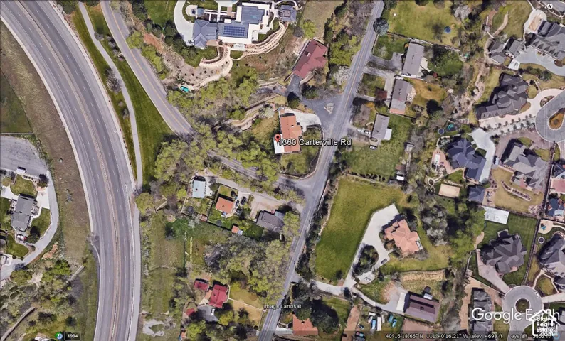 Aerial perspective featuring a multi-parcel lot, paved driveway, detached structures, and mature trees