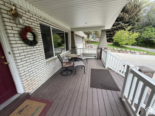 Covered front porch featuring brick siding, composite decking, white railing, and tapered pillars