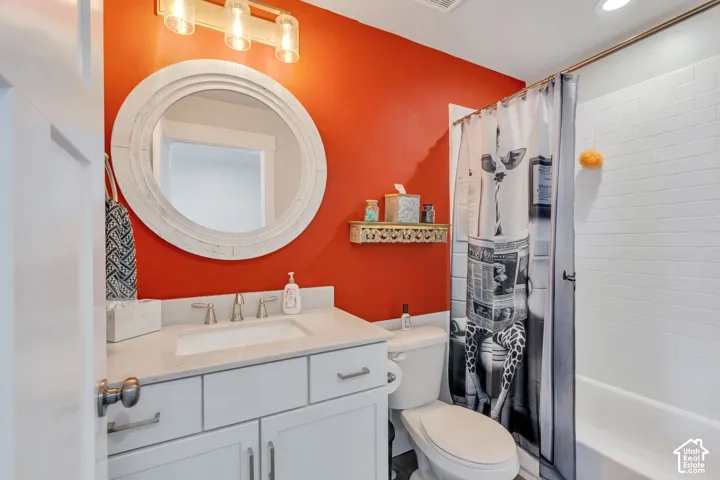 Bathroom featuring a white vanity cabinet with a stone-composite countertop, integrated rectangular sink, round decorative-frame mirror, three-bulb vanity lighting fixture, and white subway-tile tub surround