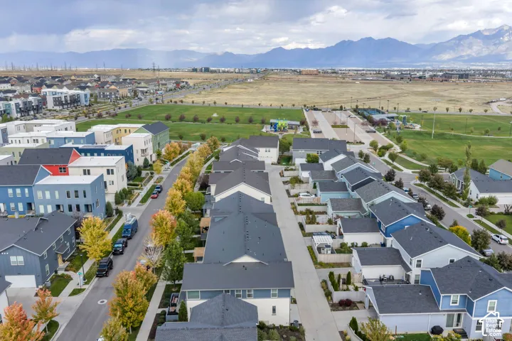 Aerial perspective featuring multi-story residential architecture, mature deciduous trees, and a mountain range backdrop