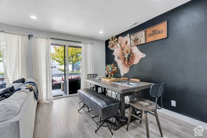 Wood-finish flooring, recessed lighting, and a distinct matte black accent wall