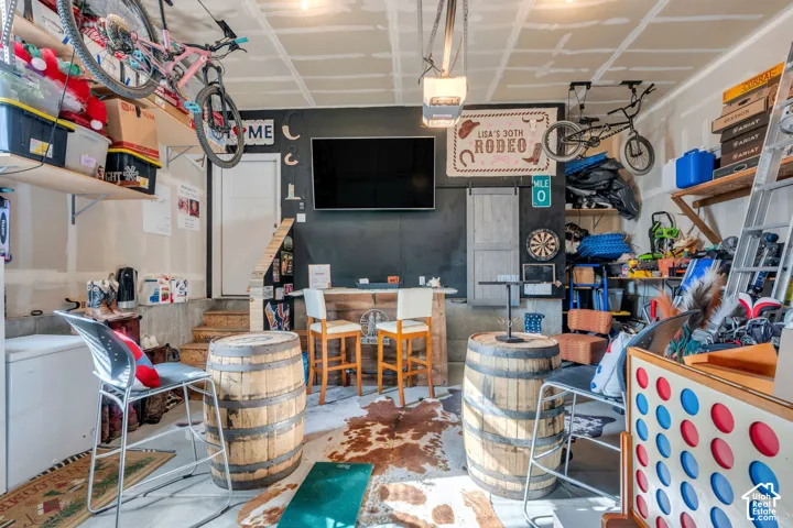 Garage space featuring an accent wall, wall-mounted television, built-in wooden bar, and overhead storage shelving