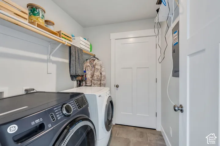Utility space featuring tile flooring, a white three-panel door, and integrated wall-mounted shelving